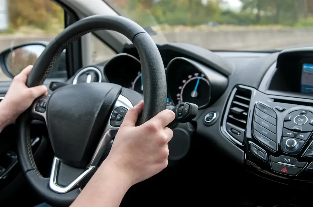 intérieur de voiture avec mains posées sur un volant