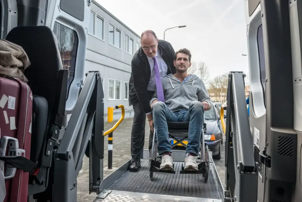 chauffeur aidant une personne en fauteuil roulant à monter dans un véhicule